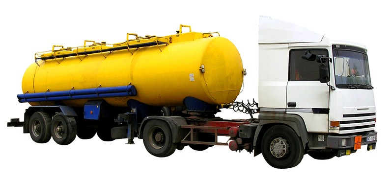 A white semi-truck with a yellow tank trailer, isolated on a white background.