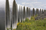 Row of large concrete pipes stacked outdoors, with grass and sky visible. Construction materials.