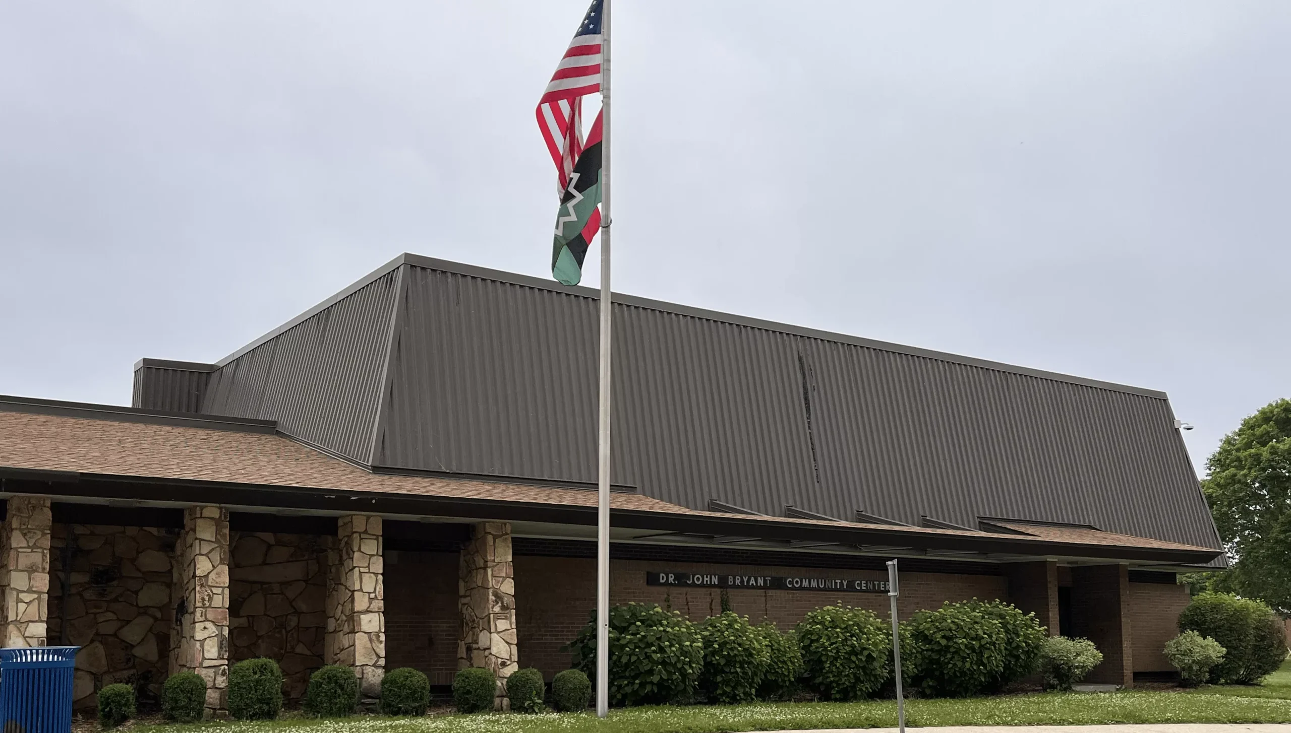 Exterior of the Dr. John Lake Community Center with US and Pan-African flags flying on a pole.