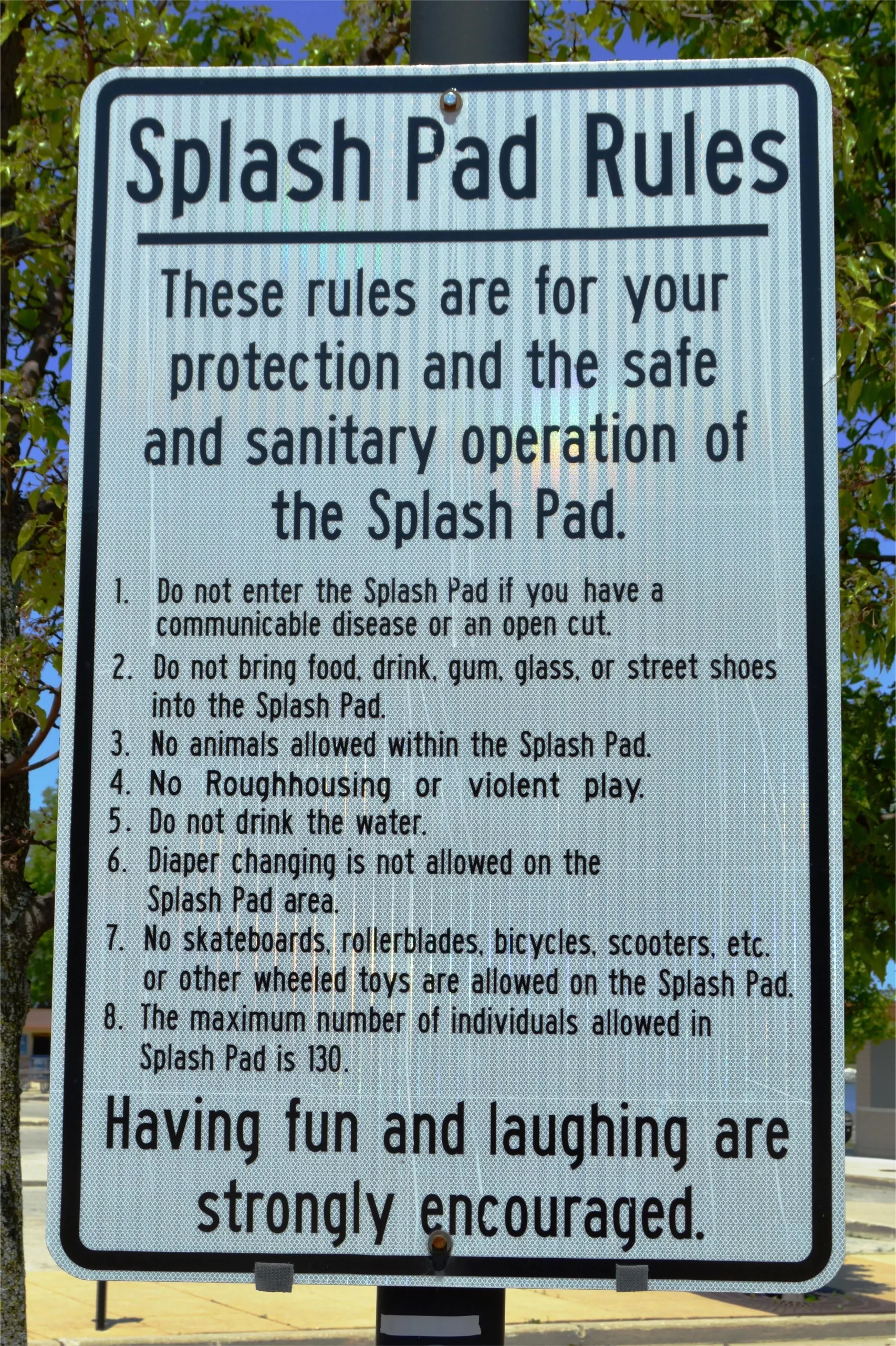 Sign listing rules for the splash pad, including no food, drinks, or animals allowed.