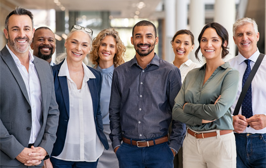 Diverse group of smiling business professionals standing together in a bright, modern office space.