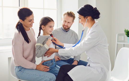 Doctor using stethoscope to examine young girl with parents present in a medical office.