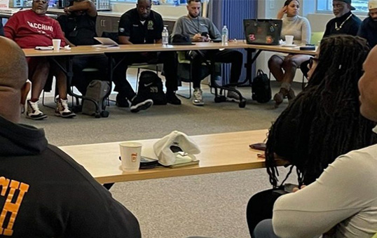 Group of diverse people seated around a table, engaged in a meeting or discussion.