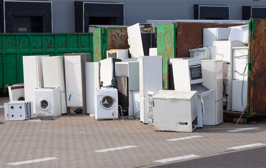 Discarded appliances, including refrigerators and washing machines, piled up for recycling or disposal.