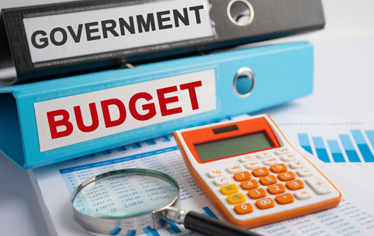 Government budget analysis with calculator, magnifying glass, and financial charts.