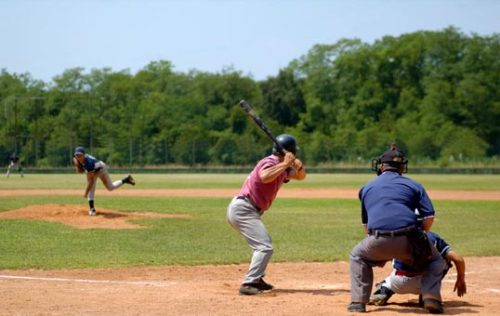 Baseball game in progress: pitcher throws, batter ready to hit, umpire watches.