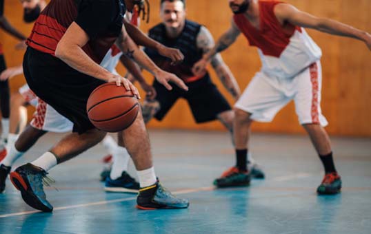Basketball player dribbling the ball during a game, surrounded by other players on the court.