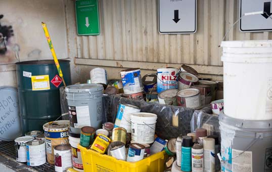 Collection of paint cans and containers at a recycling center, ready for processing and proper disposal.
