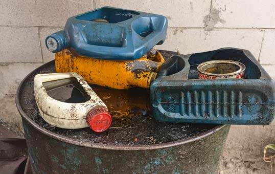 Discarded oil containers on a metal drum, showing environmental pollution and improper waste disposal.