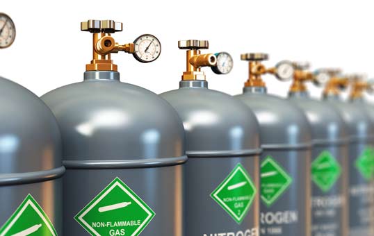 Row of gray nitrogen gas cylinders with pressure gauges and green non-flammable gas labels.