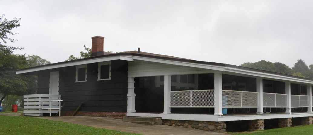 Exterior view of a single-story building with a long, covered porch supported by white columns.