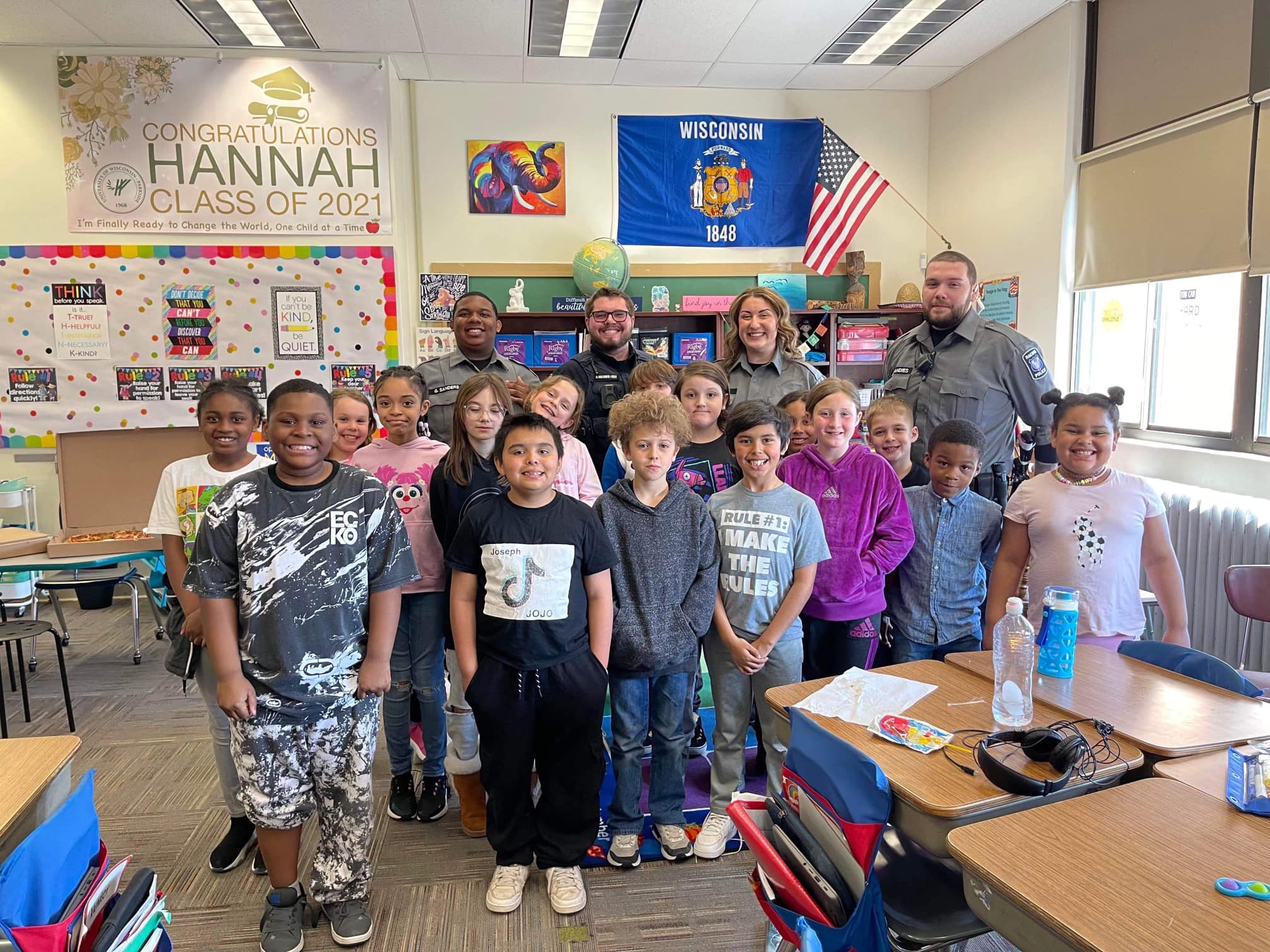 Classroom photo of elementary students with four police officers, celebrating a graduation.
