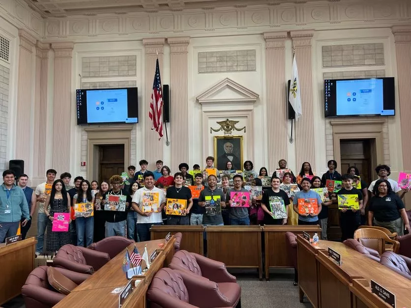 Group of students holding artwork in a government building, possibly for an exhibition or presentation.