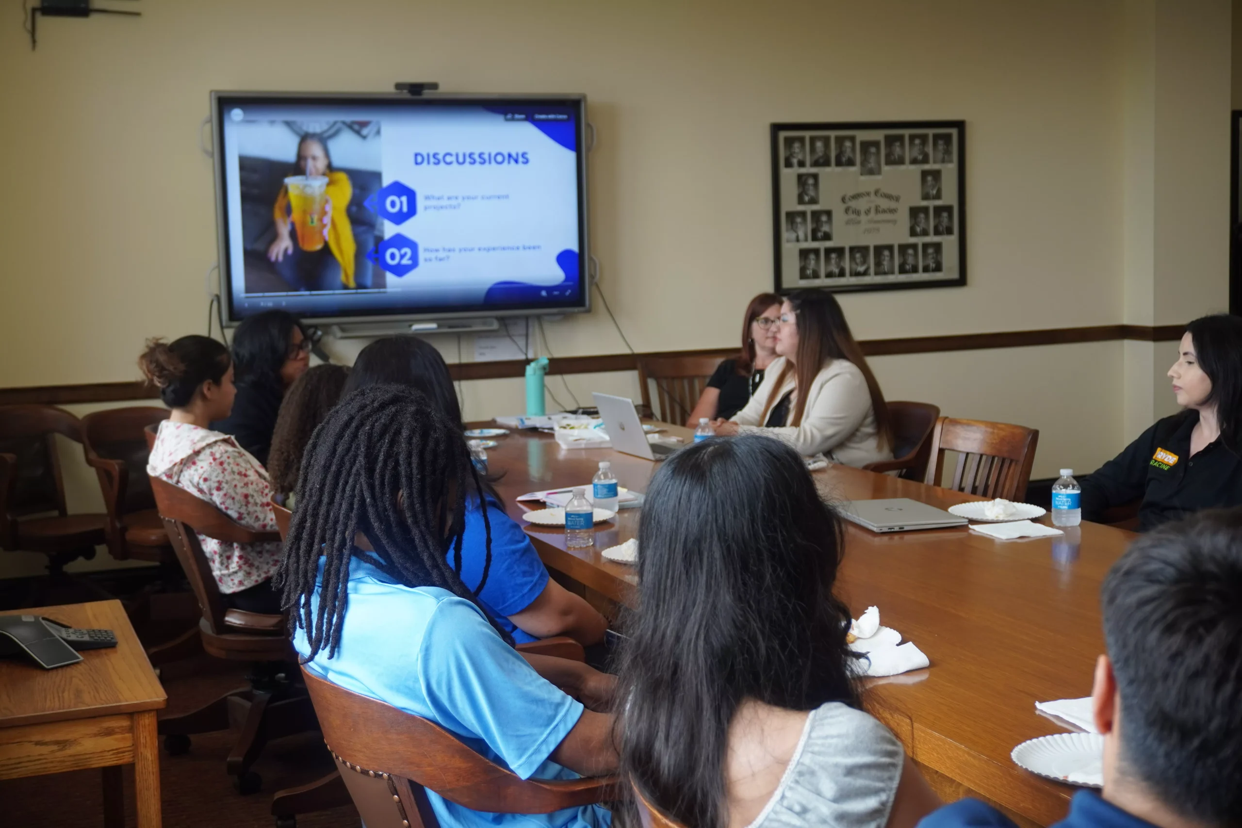 Group of people in a meeting room watching a presentation on a large screen.