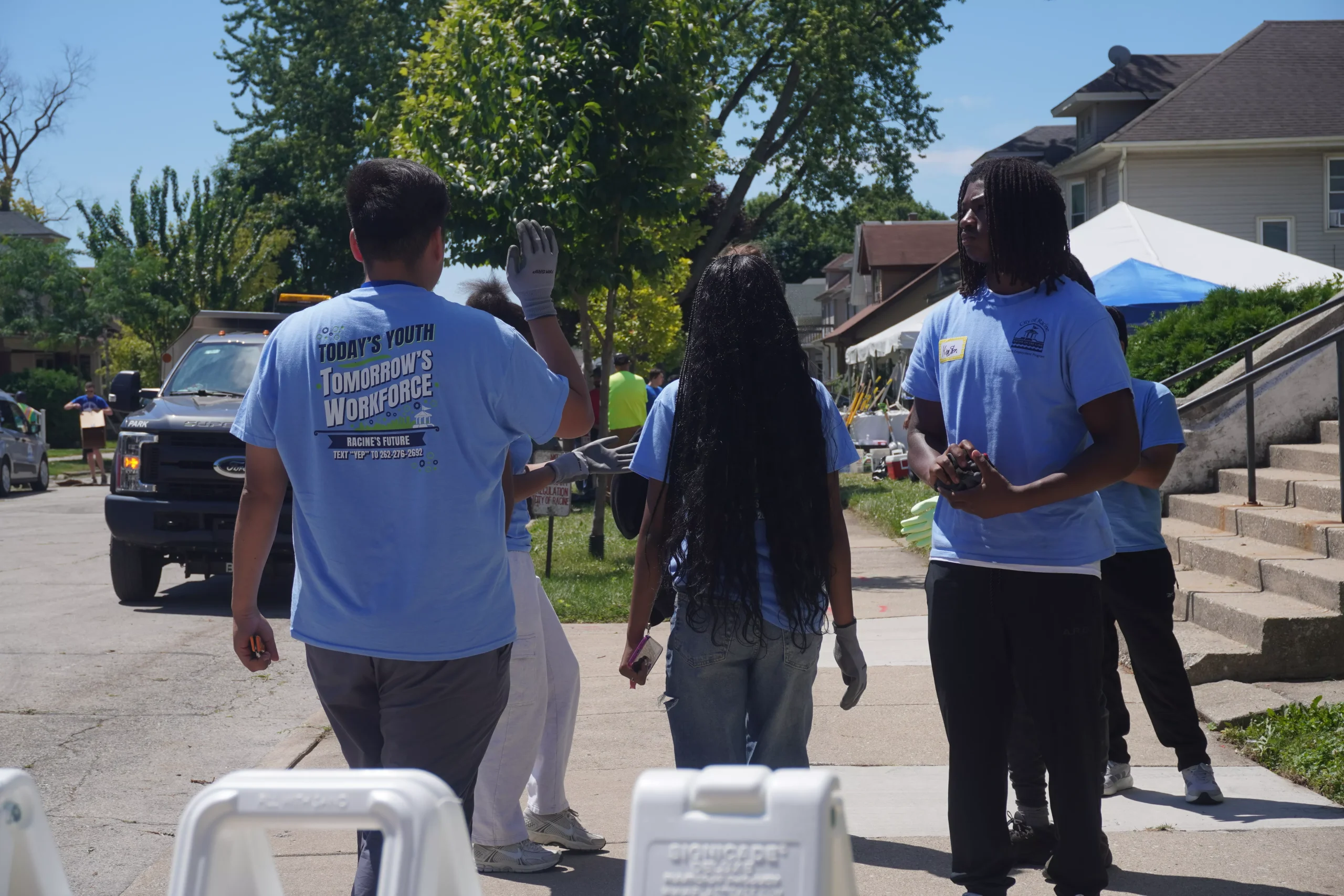 Group of volunteers wearing matching shirts at a community cleanup event on a sunny day.